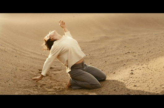 Personne agenouillée dans le sable regardant vers le ciel
