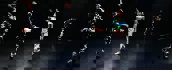 Chorégraphie de danse avec trois femmes en costumes noirs et blancs et une femme en vêtements colorés