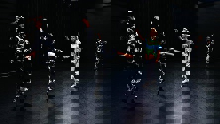 Chorégraphie de danse avec trois femmes en costumes noirs et blancs et une femme en vêtements colorés