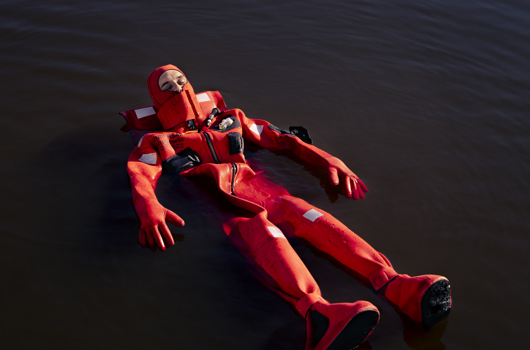 Homme en combinaison rouge qui flotte sur l'eau