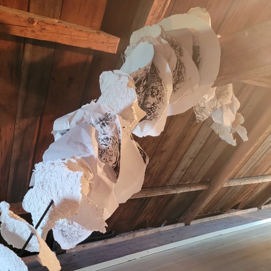 Oeuvre suspendue sur une charpente de bois